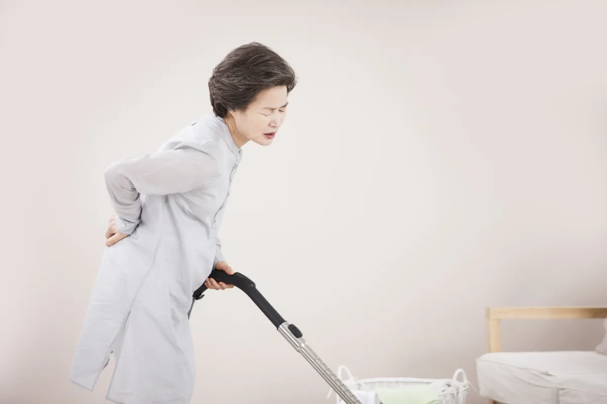 집안일을 하다 허리를 짚고 통증을 호소하는 한국인 중년 여성